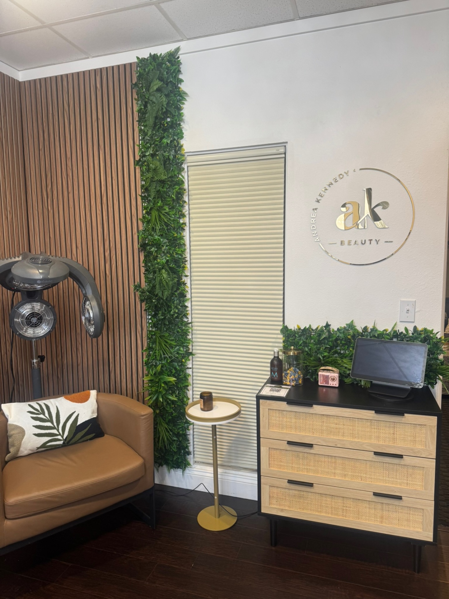 Interior of the Andrea Kennedy Beauty studio — warm wood floors, vertical garden wall, and the AK Beauty logo on the wall